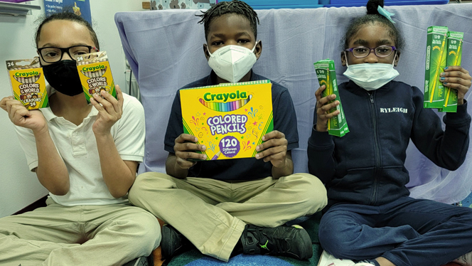 Students holding up colored pencils. Students holding up colored pencils.