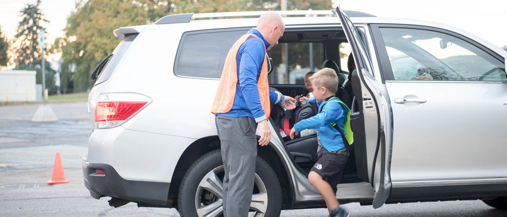 Teacher helping student into car
