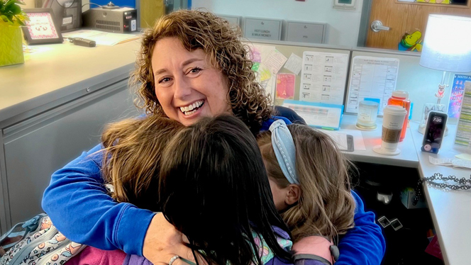 Christina Hasselkus smiling and hugging her students Christina Hasselkus smiling and hugging her students