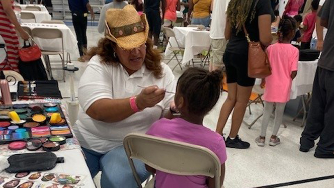 People at a face painting station. People at a face painting station.